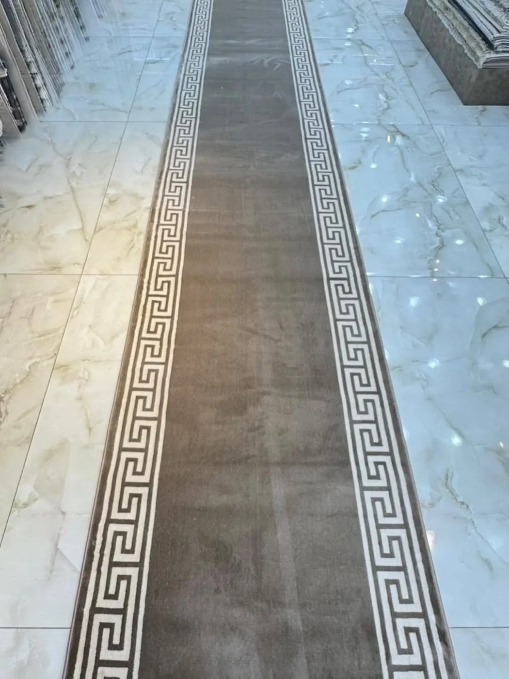 Taupe Greek key border runner on a marble hallway floor